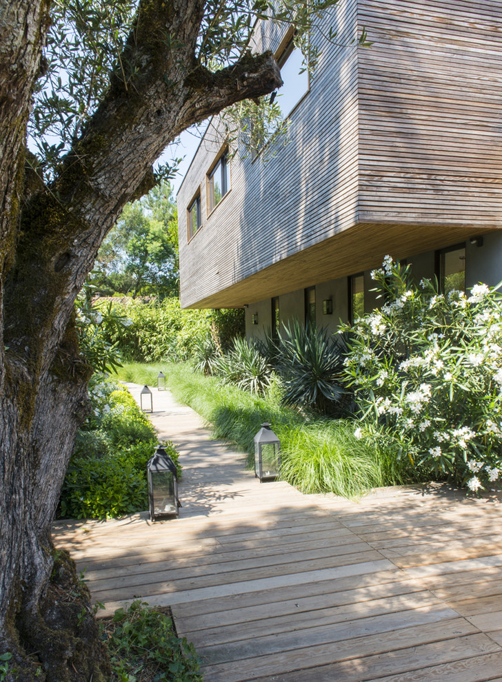 Réalisation d'un grand jardin latéral design avec une exposition partiellement ombragée et une terrasse en bois.