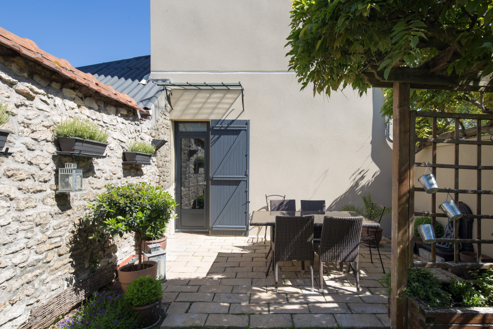 Medium sized contemporary partial sun garden in Paris with a potted garden, natural stone paving and a stone fence.