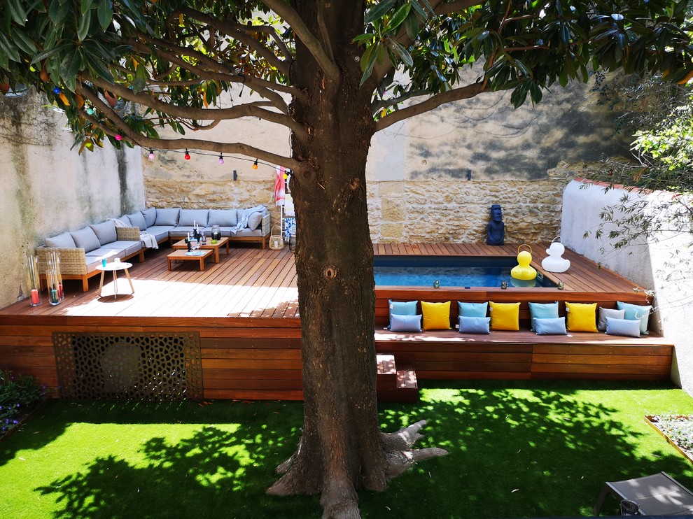 Réalisation d'un petit jardin design l'été avec un bassin, une exposition ensoleillée et une terrasse en bois.