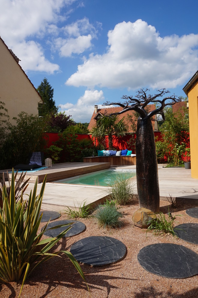 Réalisation d'un jardin arrière design de taille moyenne avec une exposition ensoleillée et une terrasse en bois.