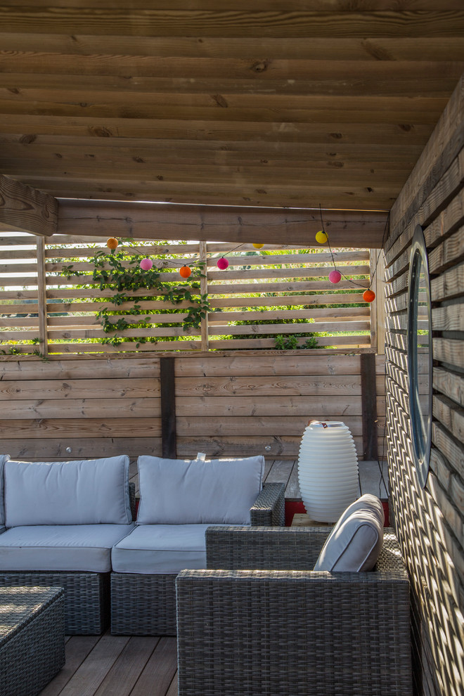 Réalisation d'un grand jardin arrière design l'été avec un mur de soutènement, une exposition ensoleillée et une terrasse en bois.