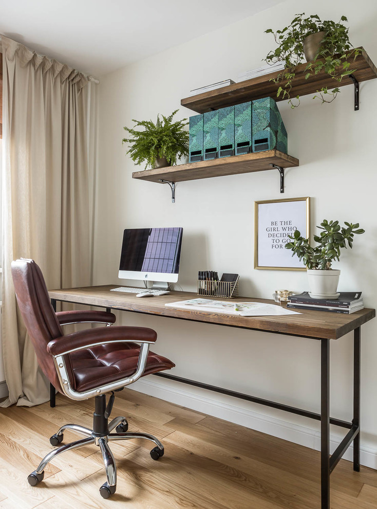 Modelo de despacho actual con paredes blancas, suelo de madera en tonos medios, escritorio independiente y suelo marrón