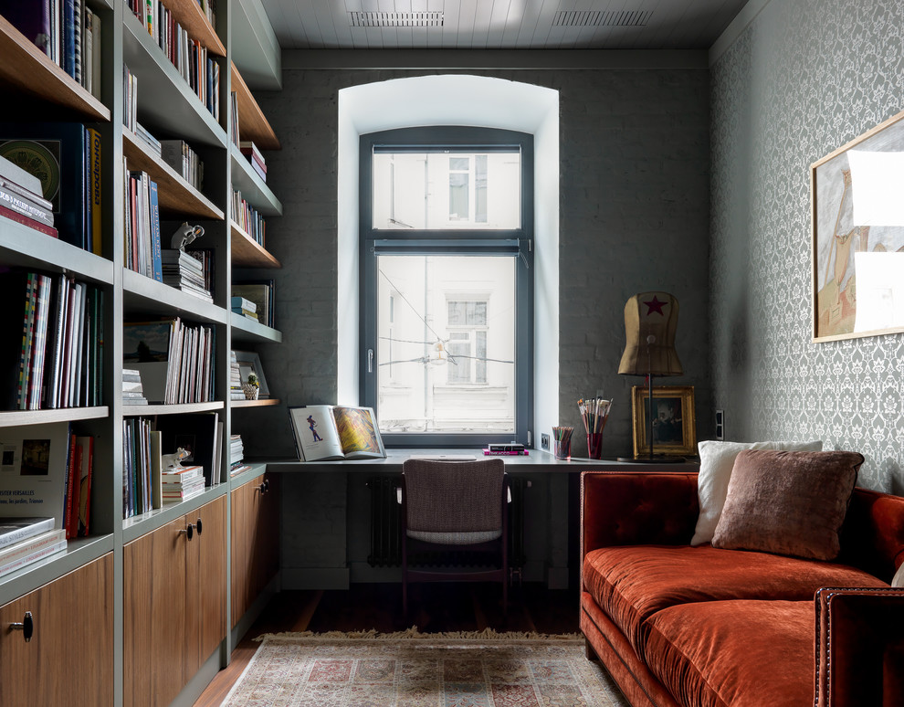На фото: домашняя библиотека в современном стиле с серыми стенами, встроенным рабочим столом и темным паркетным полом без камина с