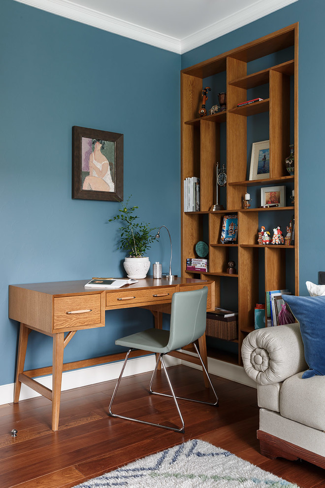 Diseño de despacho actual con paredes azules, suelo de madera en tonos medios, escritorio independiente y suelo marrón
