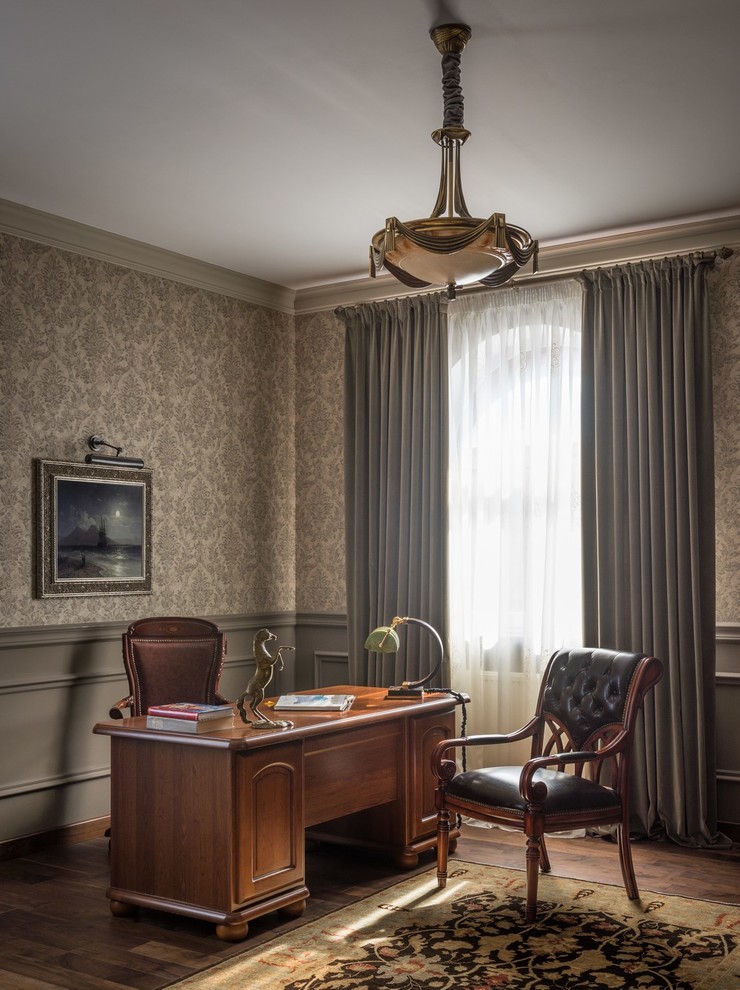 Mittelgroßes Klassisches Arbeitszimmer mit Arbeitsplatz, grauer Wandfarbe, dunklem Holzboden und freistehendem Schreibtisch in Sonstige