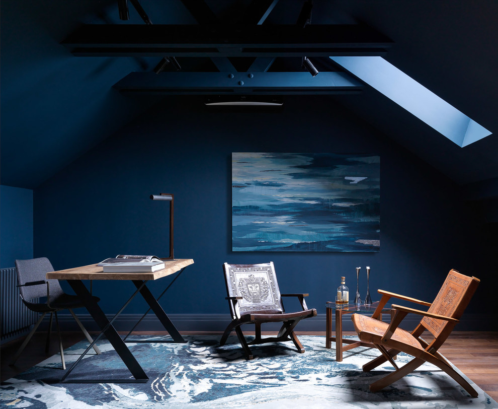 Foto på ett funkis arbetsrum, med blå väggar, mörkt trägolv, ett fristående skrivbord och brunt golv