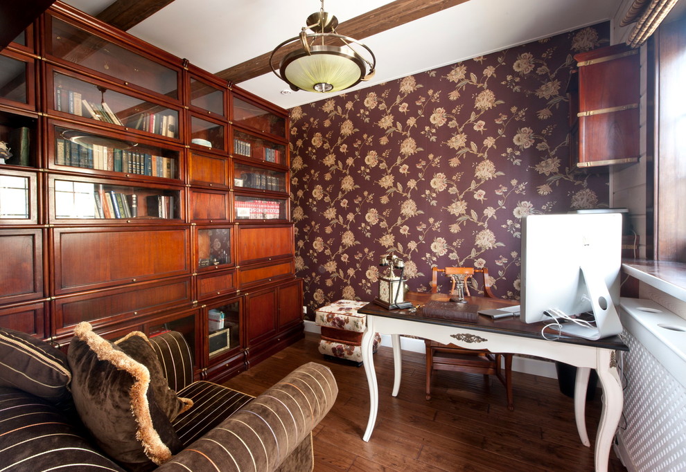 Inredning av ett klassiskt litet hemmabibliotek, med bruna väggar, mörkt trägolv och ett fristående skrivbord