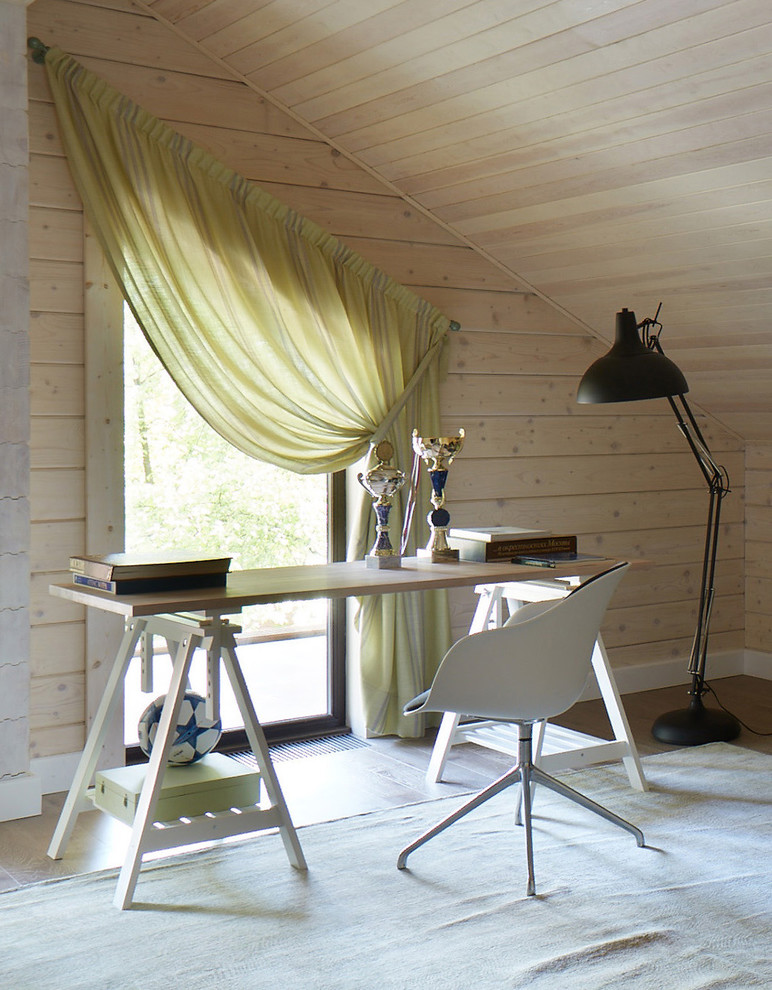 This is an example of a contemporary study in Moscow with beige walls, light hardwood flooring and a freestanding desk.