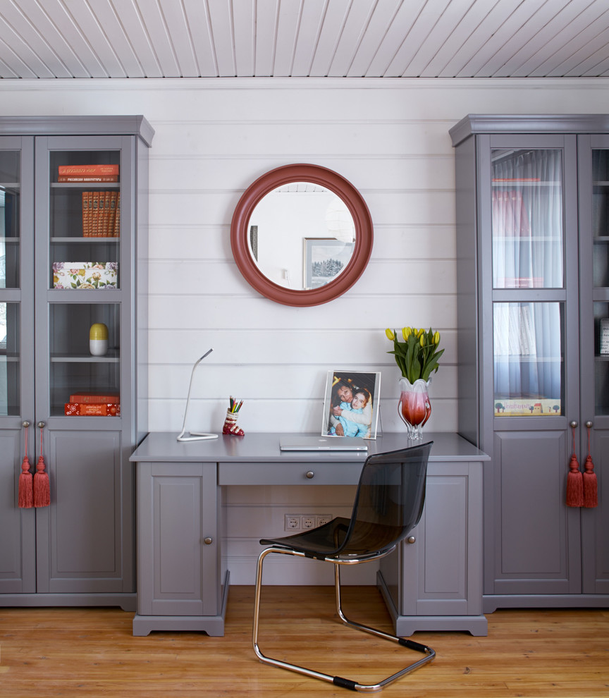 Ejemplo de despacho tradicional renovado con paredes blancas, suelo de madera en tonos medios, escritorio independiente y suelo marrón