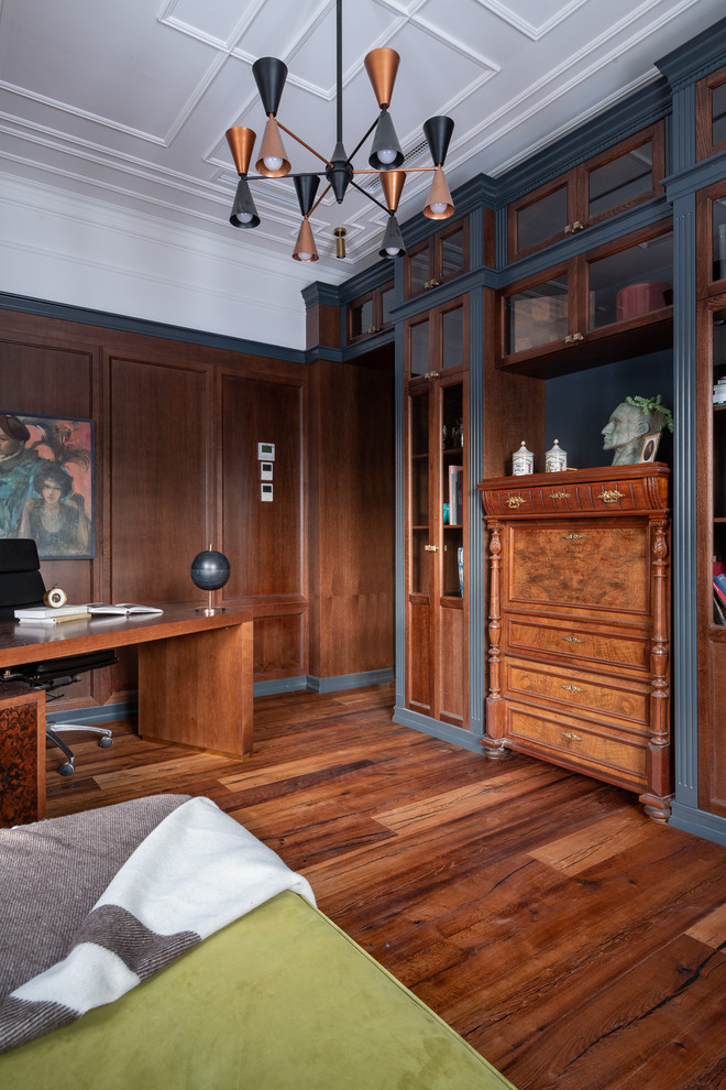 Klassisches Arbeitszimmer mit Arbeitsplatz, brauner Wandfarbe, braunem Holzboden, freistehendem Schreibtisch und braunem Boden in Sonstige