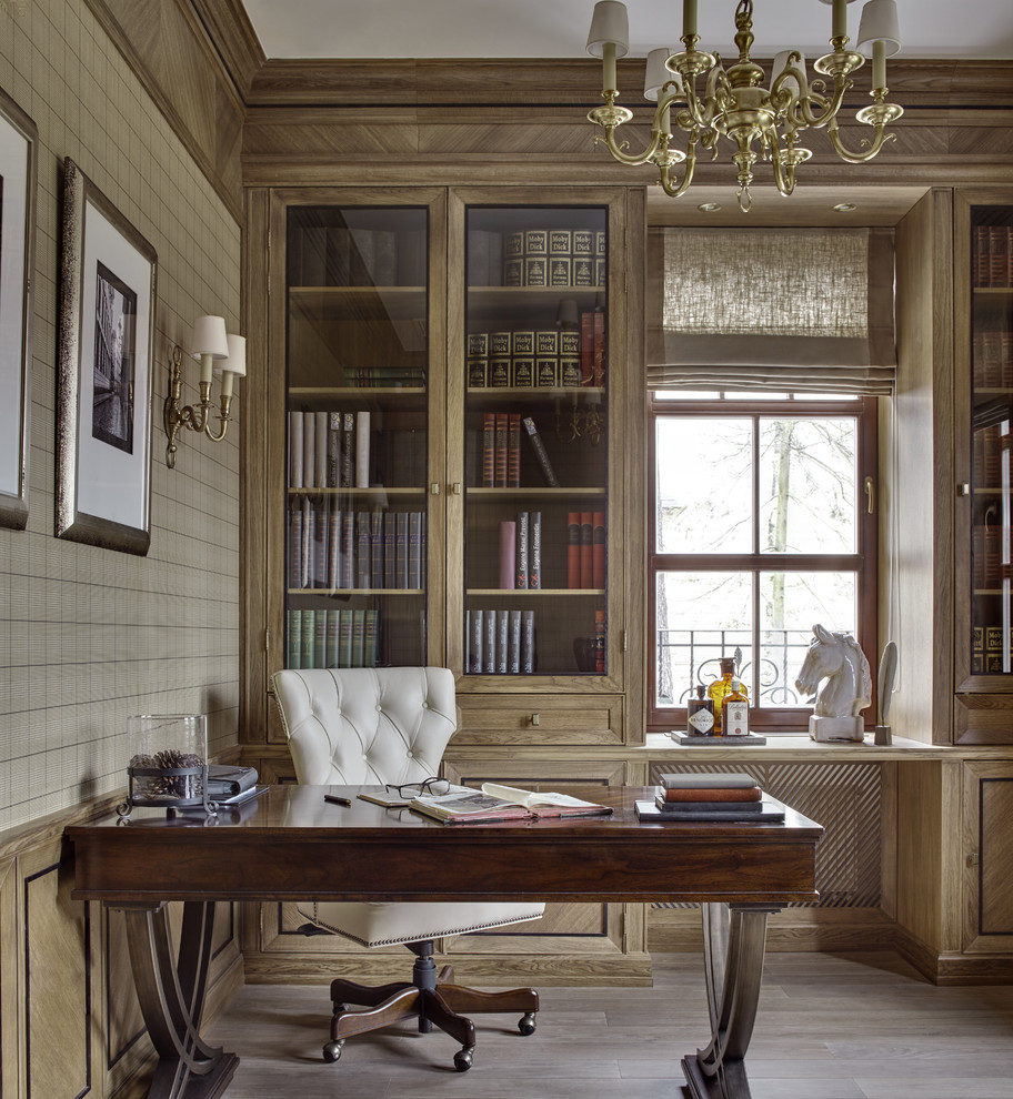 Idéer för ett klassiskt hemmabibliotek, med bruna väggar, ljust trägolv och ett fristående skrivbord