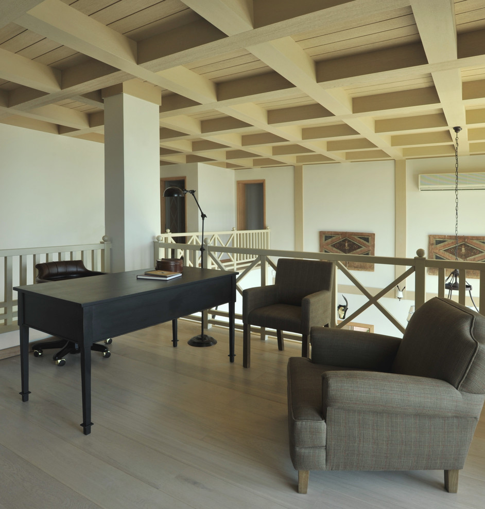 Ejemplo de despacho costero con paredes blancas, suelo de madera clara, escritorio independiente y suelo beige