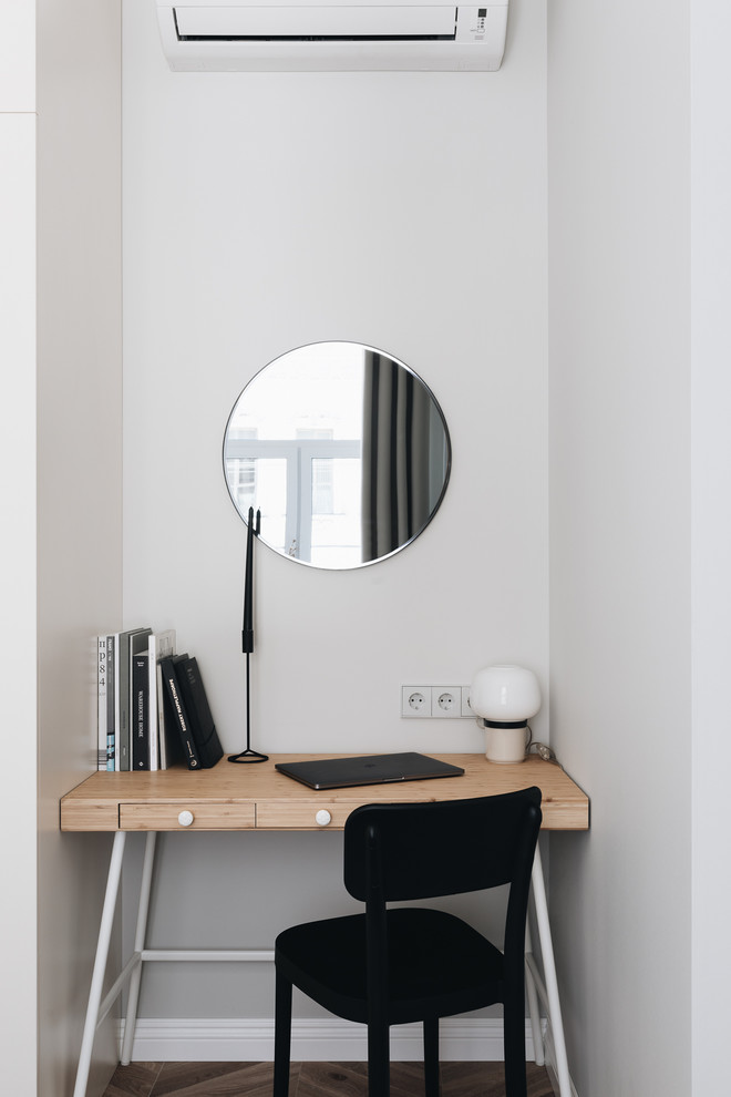 На фото: рабочее место в скандинавском стиле с серыми стенами, паркетным полом среднего тона, отдельно стоящим рабочим столом и коричневым полом с