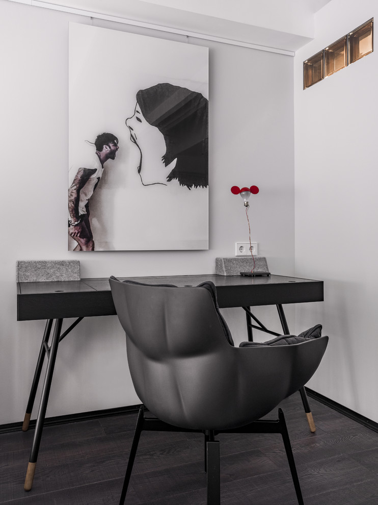 Ejemplo de despacho actual con paredes blancas, suelo de madera oscura, escritorio independiente y suelo negro
