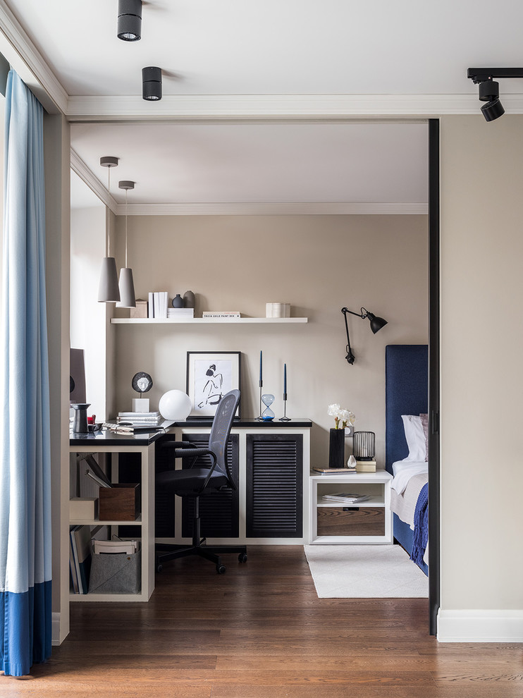 Diseño de despacho actual pequeño con paredes beige, suelo de madera en tonos medios, escritorio empotrado y suelo marrón