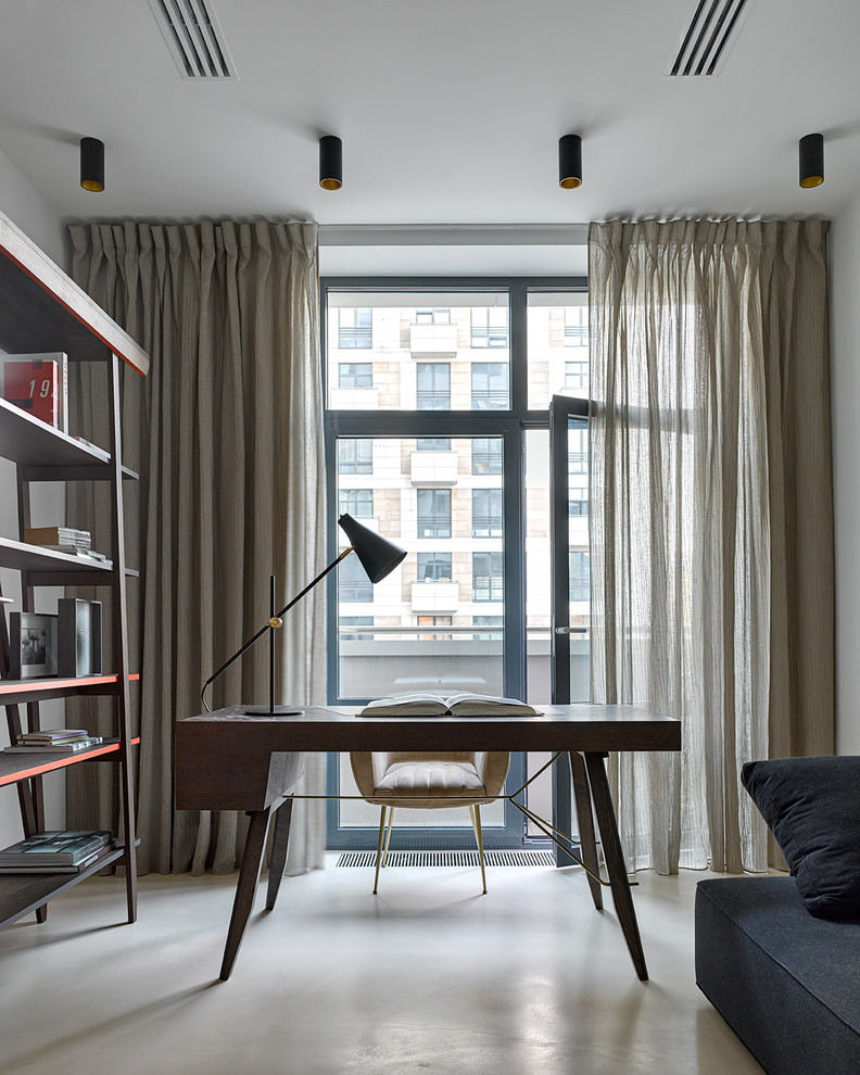Imagen de despacho contemporáneo de tamaño medio con paredes grises, suelo de cemento, escritorio independiente y suelo beige