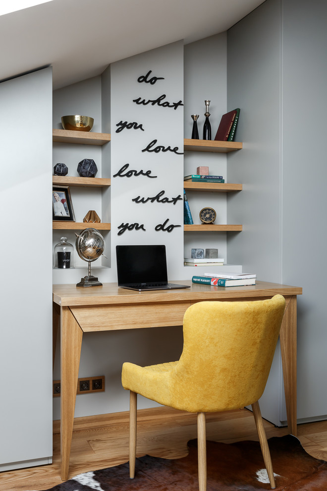 Diseño de despacho actual pequeño con paredes grises, escritorio empotrado y suelo de madera clara