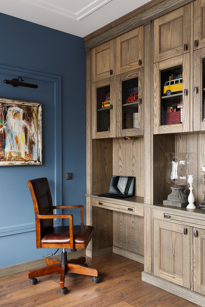 Imagen de despacho clásico con paredes azules, suelo de madera en tonos medios, escritorio empotrado y suelo marrón