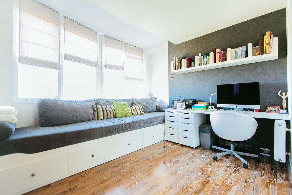 Foto de despacho actual de tamaño medio con suelo de madera en tonos medios y escritorio independiente