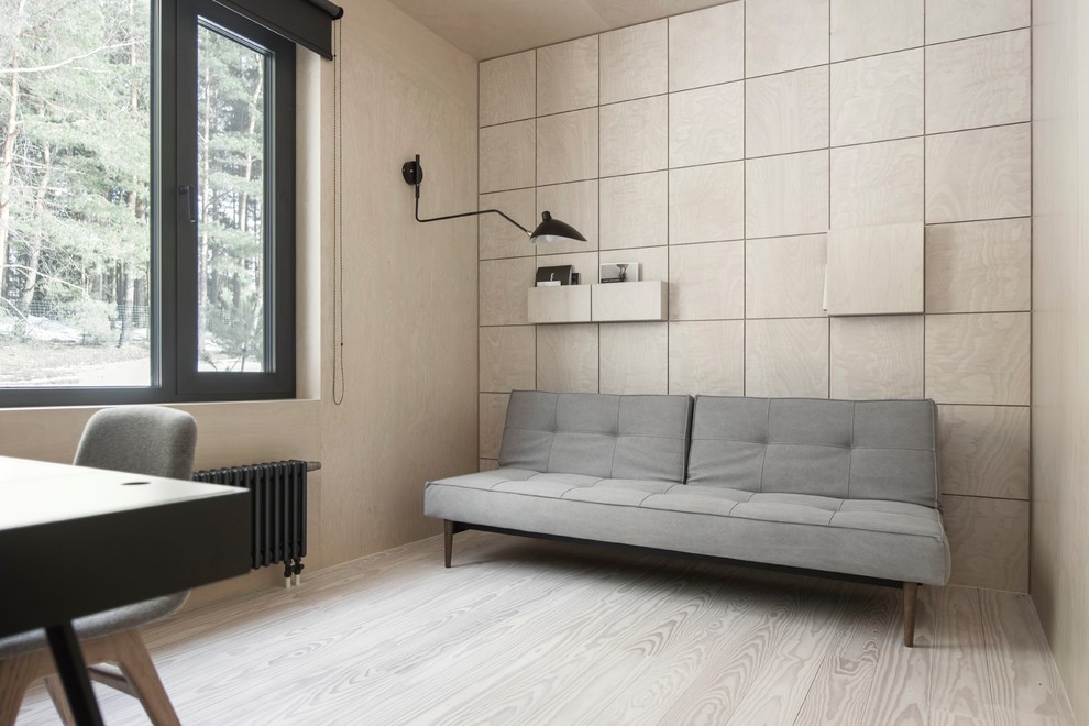 Kleines Lesezimmer mit beiger Wandfarbe, gebeiztem Holzboden, freistehendem Schreibtisch und beigem Boden