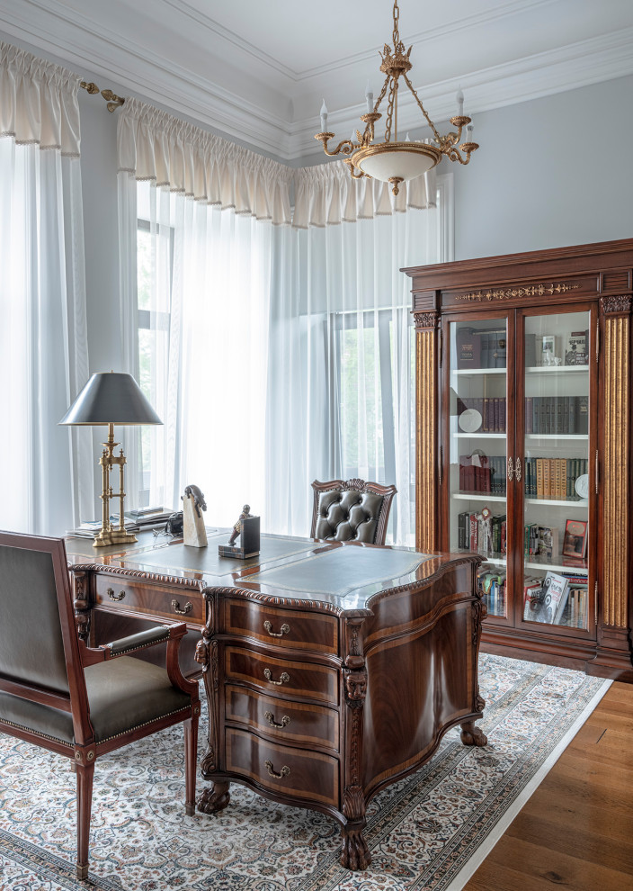 Idee per un ufficio classico con pareti grigie, pavimento in legno massello medio, scrivania autoportante e pavimento marrone