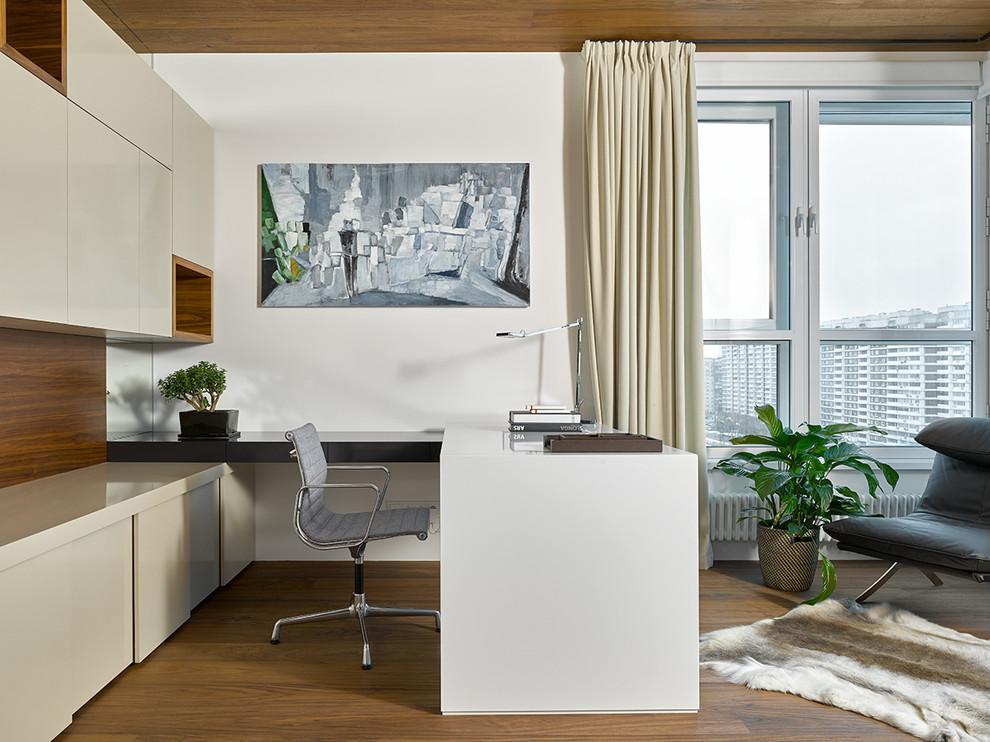 Источник вдохновения для домашнего уюта: рабочее место в современном стиле с белыми стенами, паркетным полом среднего тона, встроенным рабочим столом и коричневым полом
