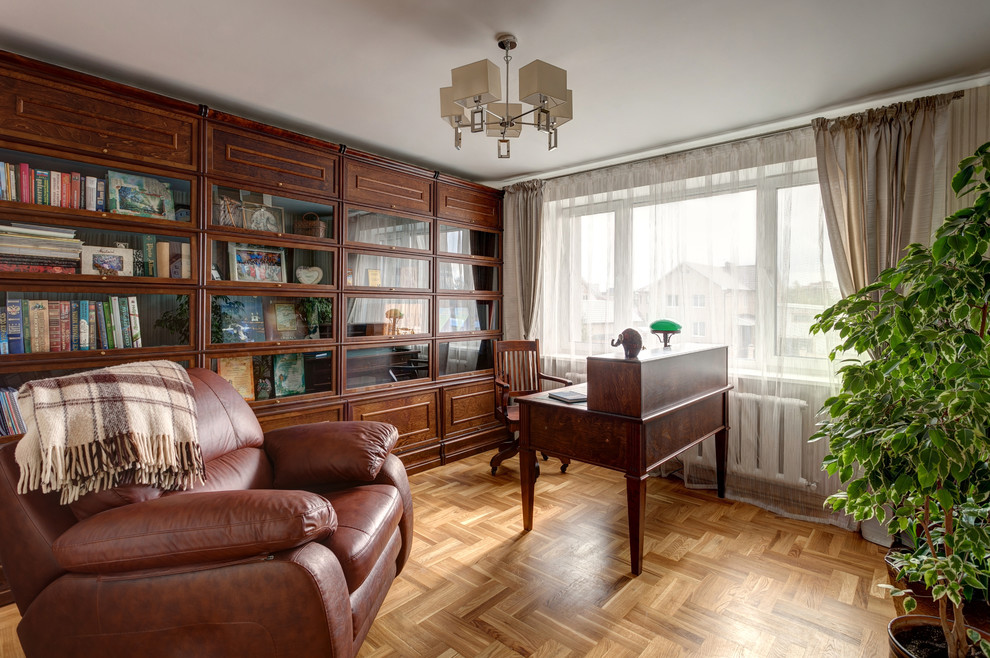 Diseño de despacho clásico con paredes beige, suelo de madera en tonos medios y escritorio independiente