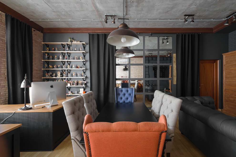 他の地域にあるお手頃価格の広いインダストリアルスタイルのおしゃれな書斎 (黒い壁、ラミネートの床、自立型机、茶色い床) の写真