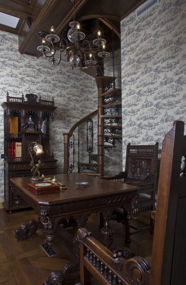 Klassisk inredning av ett hemmabibliotek, med grå väggar, mellanmörkt trägolv och ett fristående skrivbord
