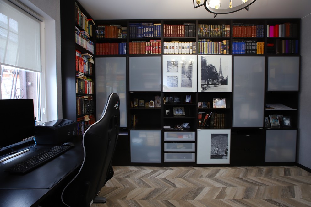 На фото: домашняя библиотека среднего размера в современном стиле с серыми стенами, полом из ламината, отдельно стоящим рабочим столом и бежевым полом с