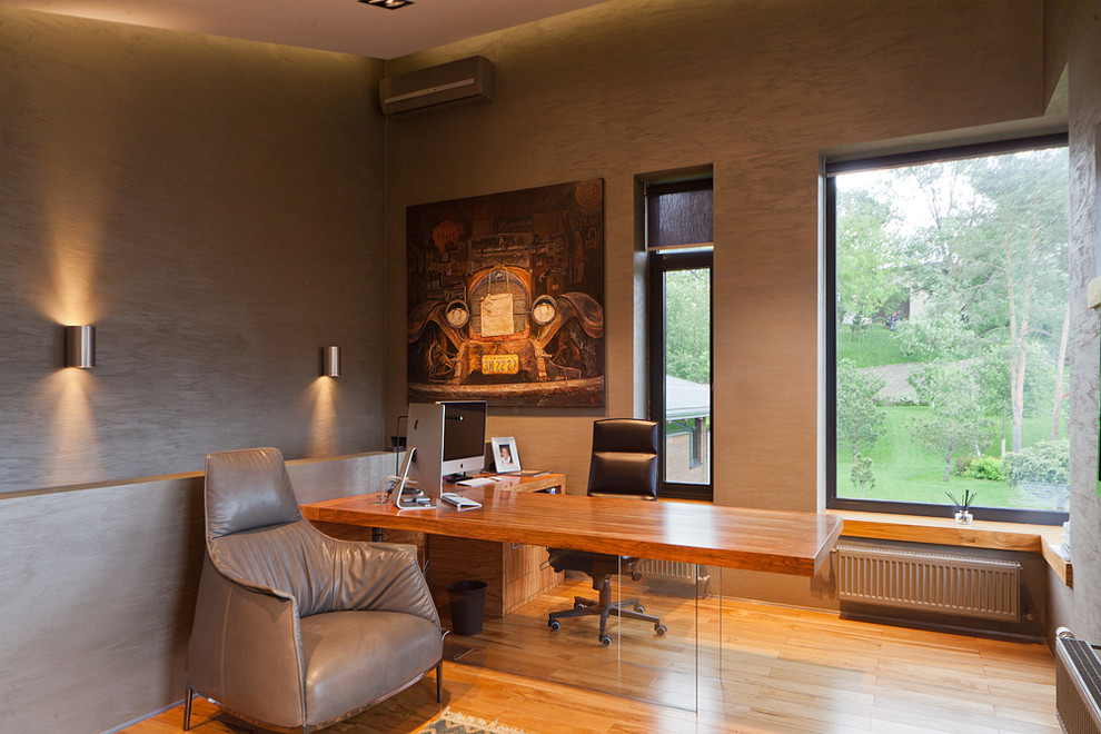 Modernes Arbeitszimmer mit Arbeitsplatz, grauer Wandfarbe, braunem Holzboden und freistehendem Schreibtisch in Moskau