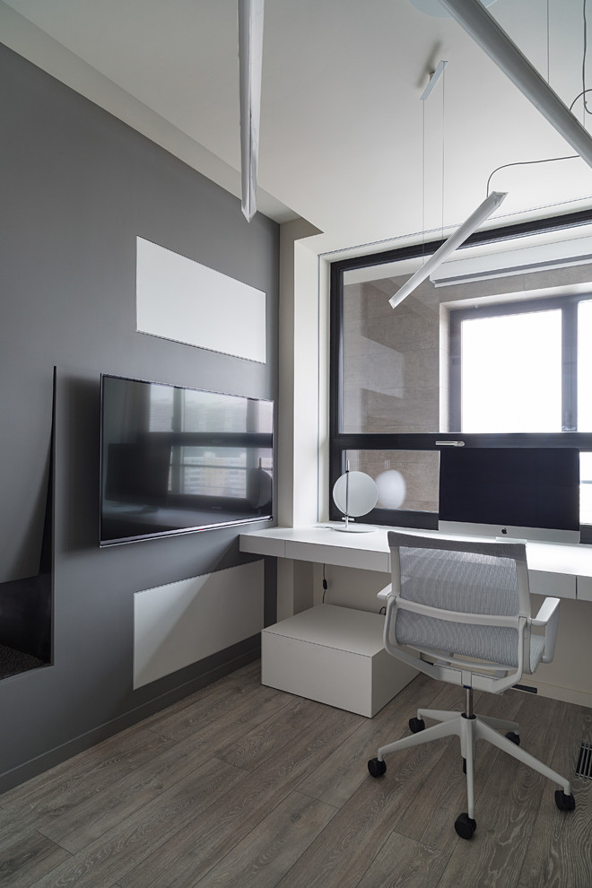 Inspiration pour un bureau nordique avec un mur gris, une cheminée double-face, un bureau intégré et un sol en bois brun.