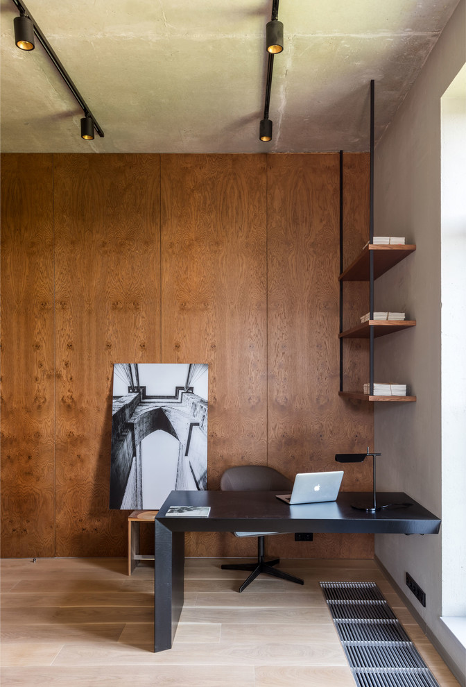 Inspiration för ett industriellt hemmabibliotek, med ljust trägolv, ett inbyggt skrivbord, beiget golv och grå väggar