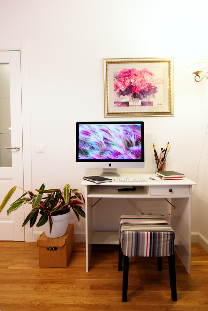 Idéer för små minimalistiska hemmabibliotek, med vita väggar, ljust trägolv, ett fristående skrivbord och gult golv