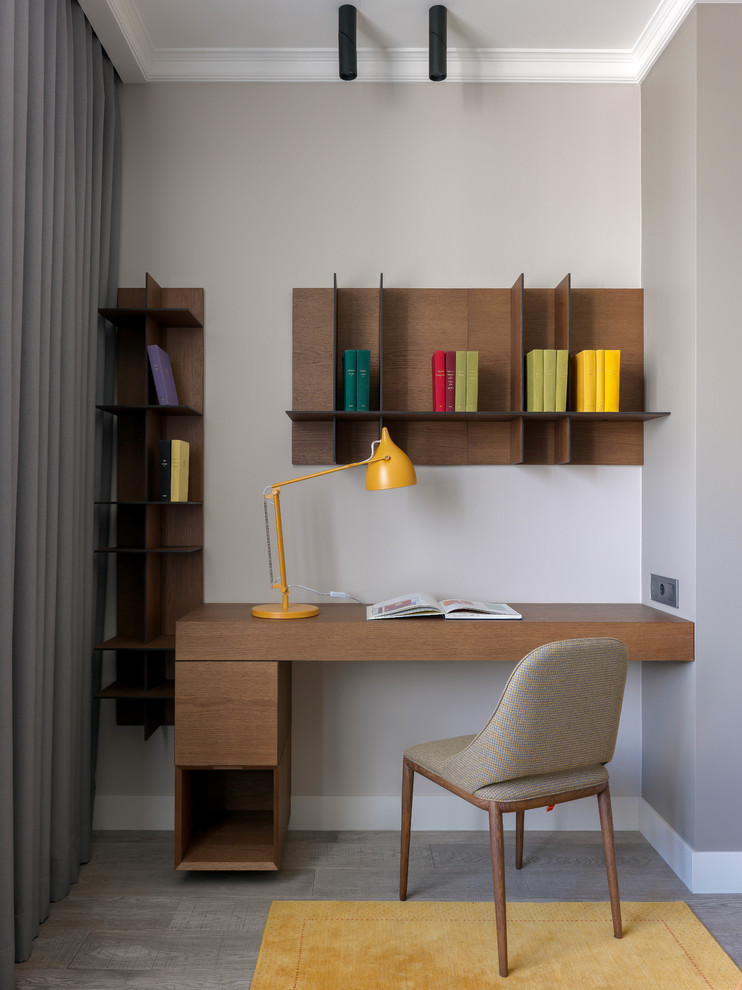 Inspiration för ett litet funkis hemmabibliotek, med grå väggar, mellanmörkt trägolv, ett inbyggt skrivbord och grått golv