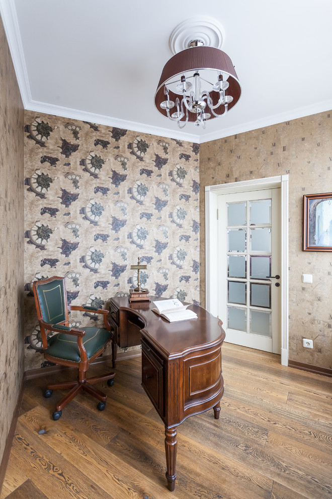 Imagen de despacho clásico con paredes beige, suelo de madera en tonos medios y escritorio independiente