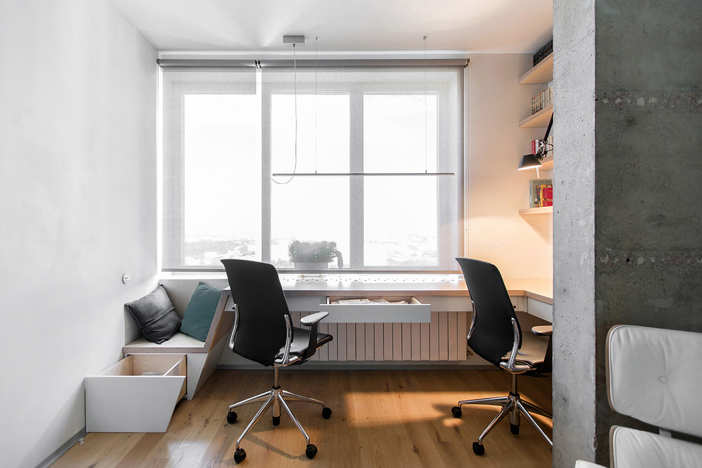 Идея дизайна: рабочее место в современном стиле с белыми стенами, паркетным полом среднего тона и встроенным рабочим столом