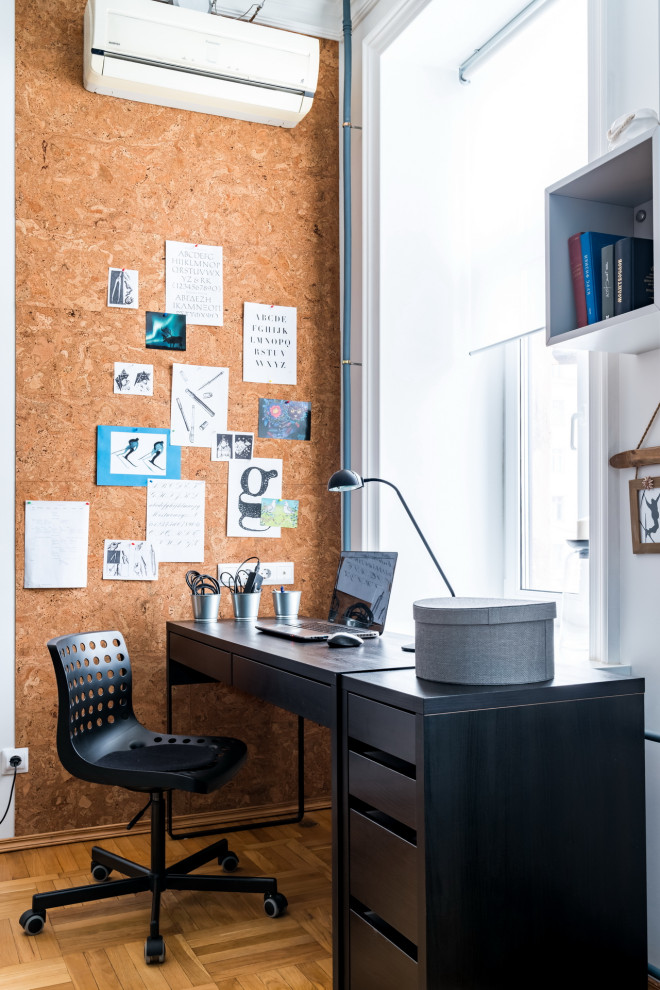 Diseño de despacho actual de tamaño medio con paredes blancas, suelo de madera en tonos medios, escritorio independiente y suelo marrón