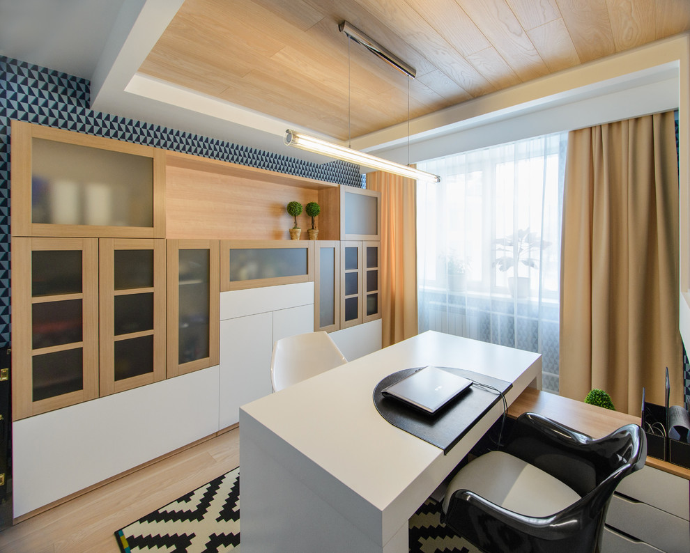 Inspiration för små moderna hemmabibliotek, med blå väggar, ljust trägolv och ett fristående skrivbord