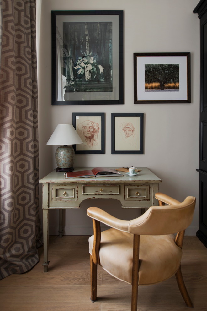 Inredning av ett eklektiskt mellanstort hemmabibliotek, med grå väggar, ljust trägolv, ett fristående skrivbord och beiget golv