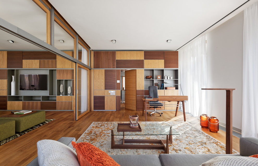 Diseño de despacho actual grande sin chimenea con paredes blancas, suelo de madera en tonos medios, suelo marrón y escritorio independiente