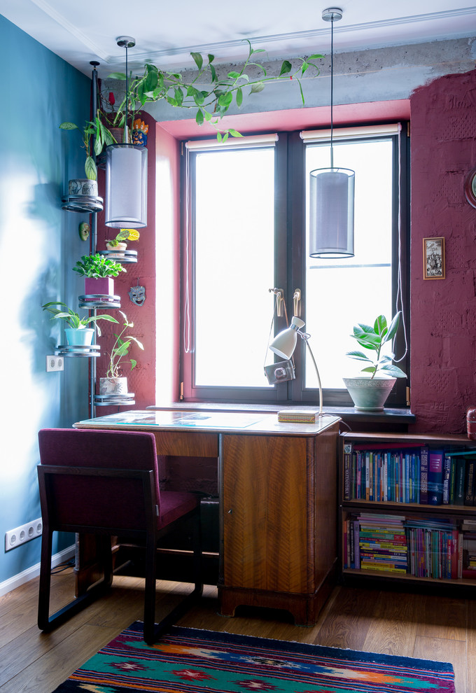 Diseño de despacho moderno con paredes multicolor, suelo de madera en tonos medios y escritorio independiente