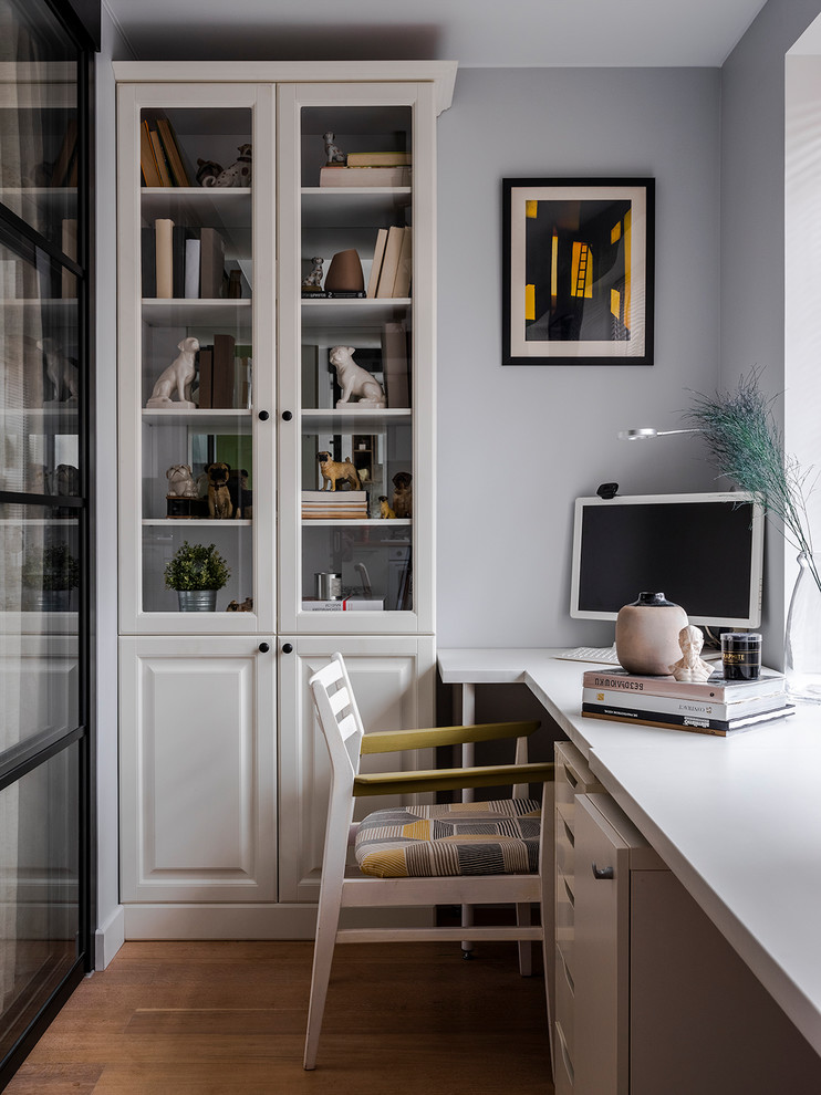 Стильный дизайн: кабинет в современном стиле с серыми стенами, паркетным полом среднего тона, отдельно стоящим рабочим столом и коричневым полом - последний тренд