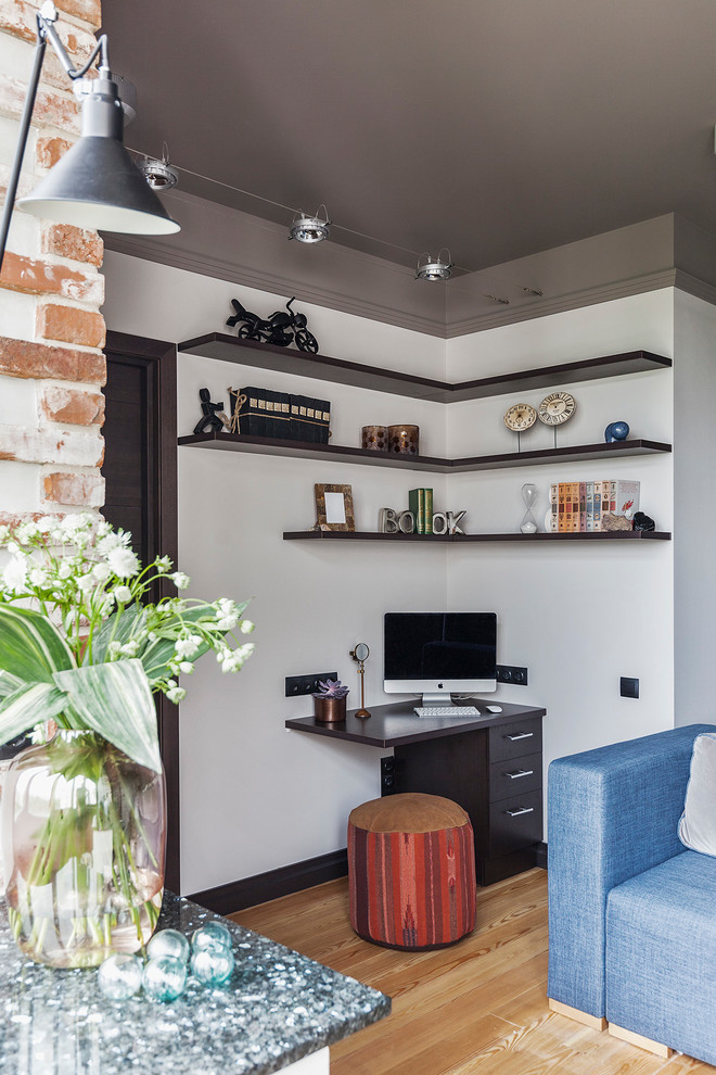 Cette image montre un petit bureau design avec un sol en bois brun, un bureau intégré, un mur blanc et un sol beige.