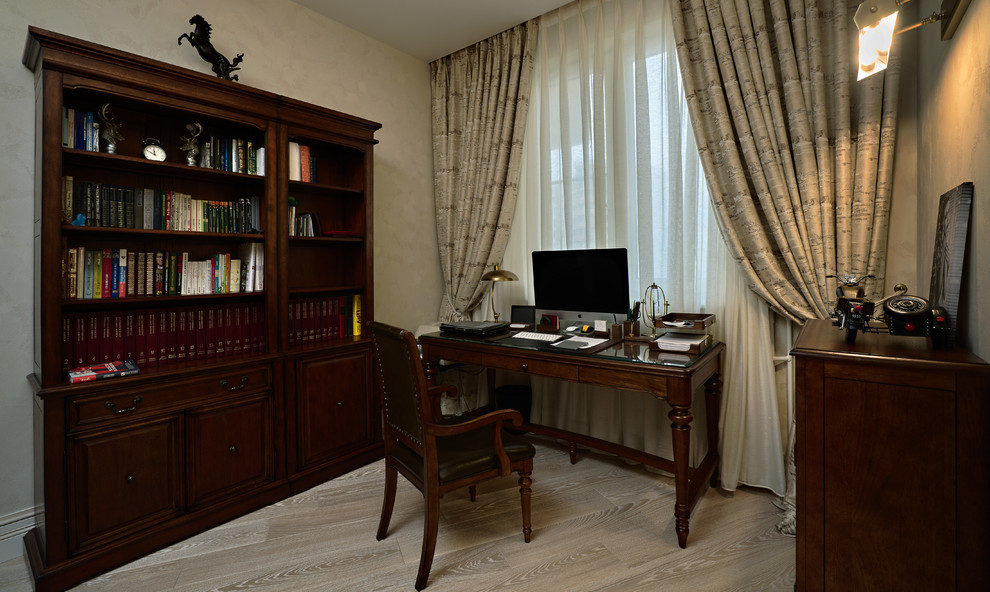 Modelo de despacho clásico pequeño con paredes beige, escritorio independiente, suelo beige y suelo de madera clara