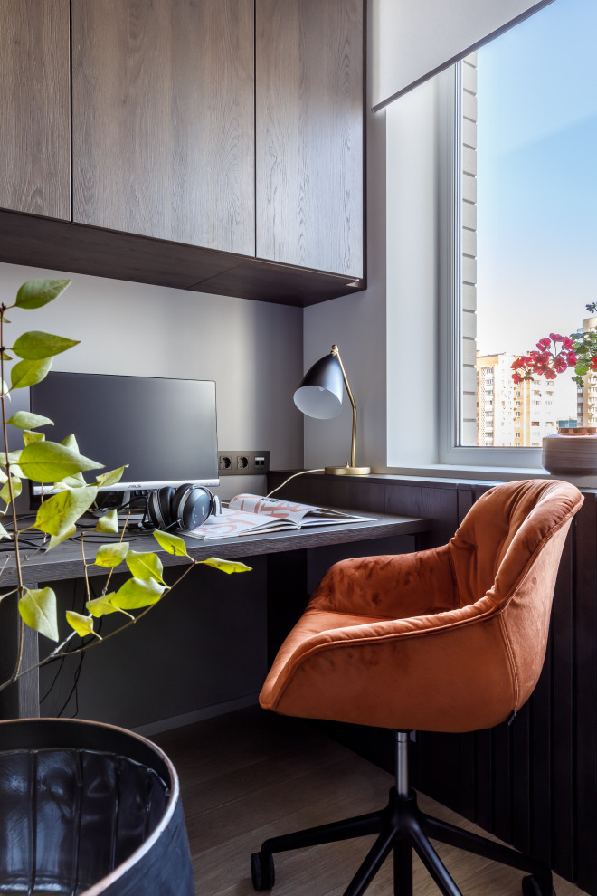 Ejemplo de despacho contemporáneo con paredes grises, suelo de madera clara, escritorio empotrado y suelo beige