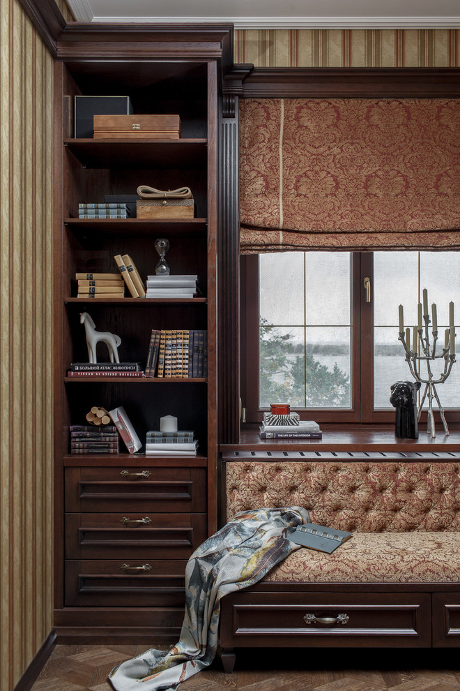 Immagine di uno studio di medie dimensioni con libreria, pareti rosse, pavimento in legno massello medio, scrivania autoportante e pavimento marrone