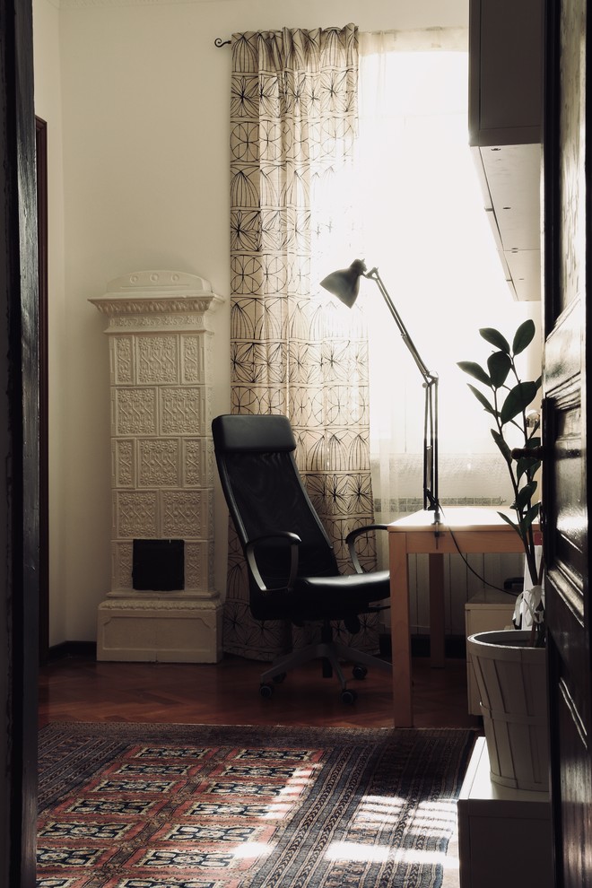 Inredning av ett klassiskt mellanstort hemmastudio, med vita väggar, mellanmörkt trägolv, ett fristående skrivbord och brunt golv