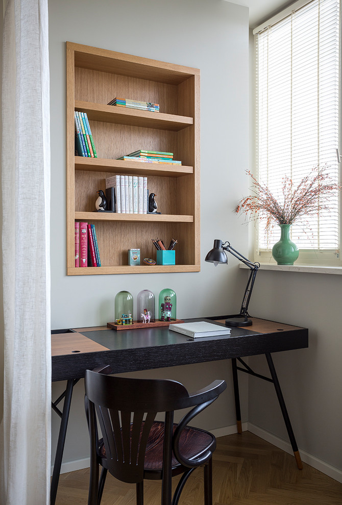 Idéer för att renovera ett litet funkis hemmabibliotek, med grå väggar, mellanmörkt trägolv och ett fristående skrivbord