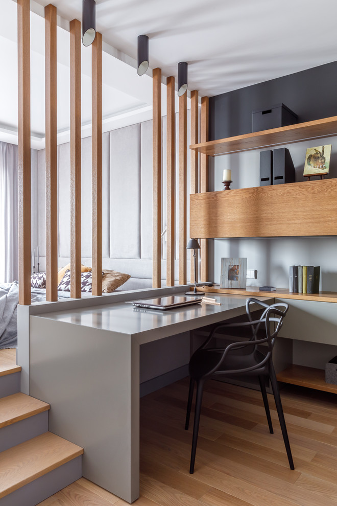 Источник вдохновения для домашнего уюта: рабочее место в современном стиле с серыми стенами, паркетным полом среднего тона, встроенным рабочим столом и коричневым полом без камина